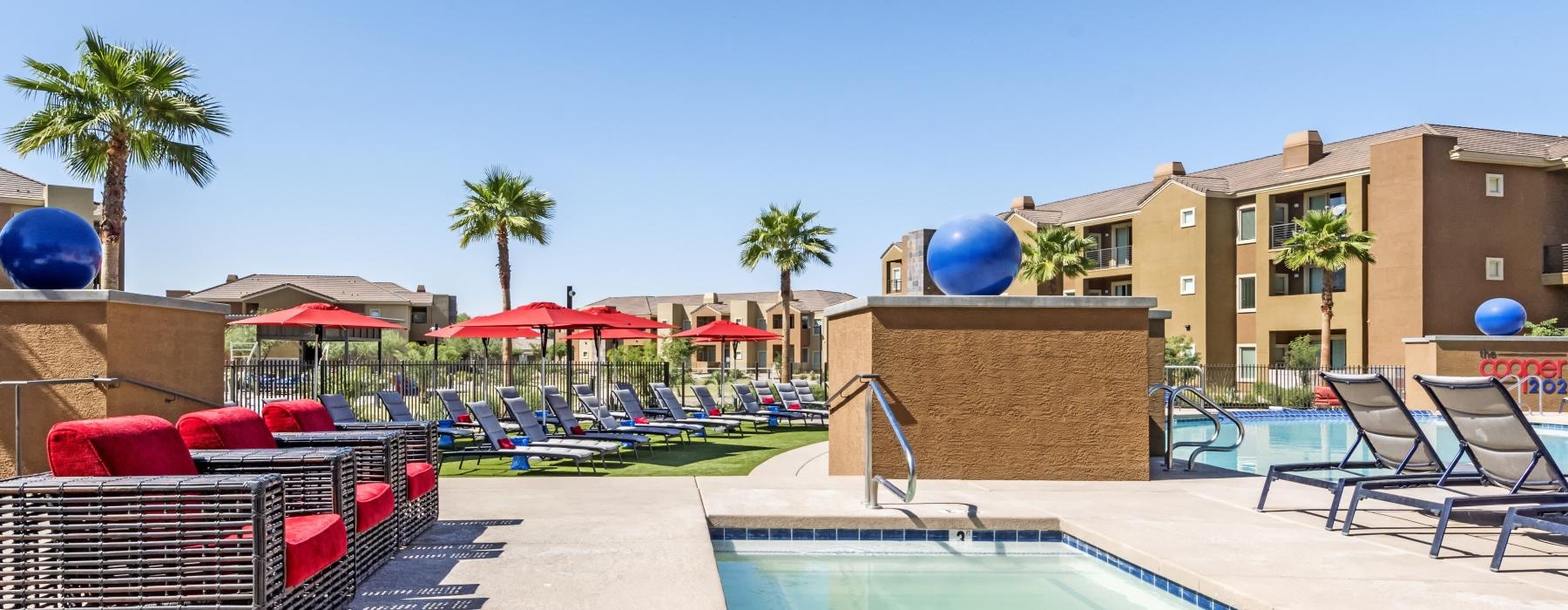 a pool with a deck and chairs by it and buildings in the background